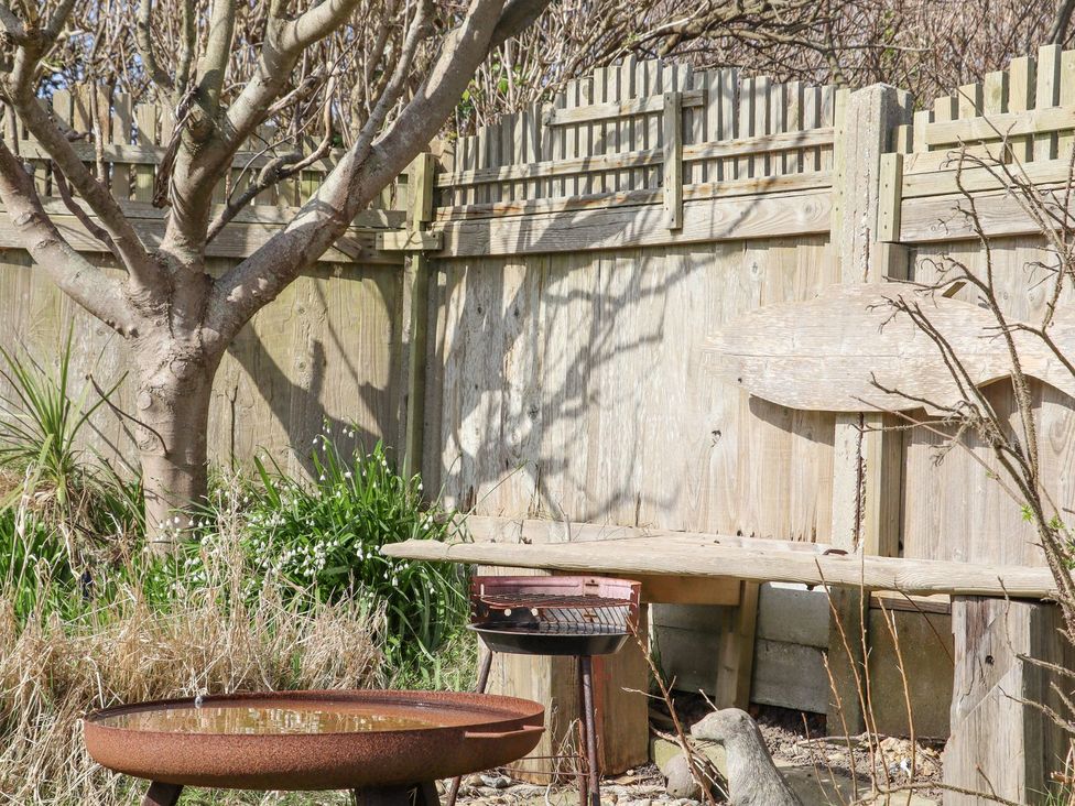 A garden with a tree, bench, birdbath, and grill at Greengates in Rye
