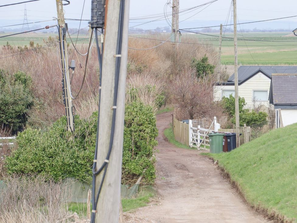 A dirt path leading to houses with power lines at Greengates in Rye