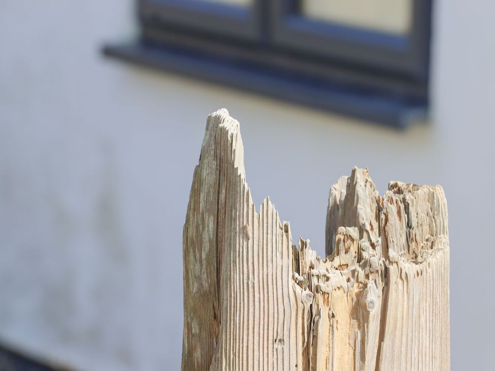 A broken wood post with a building in the background at Greengates in Rye