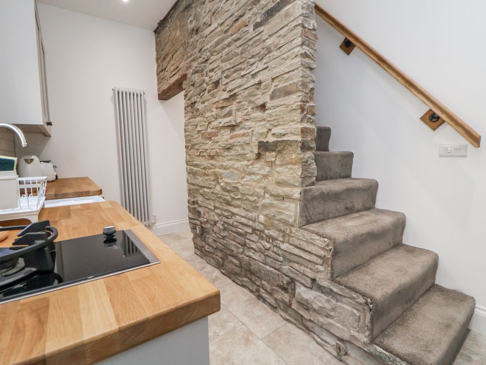 A kitchen with a stone wall and stairs leading up at 10 South Street in Rossendale