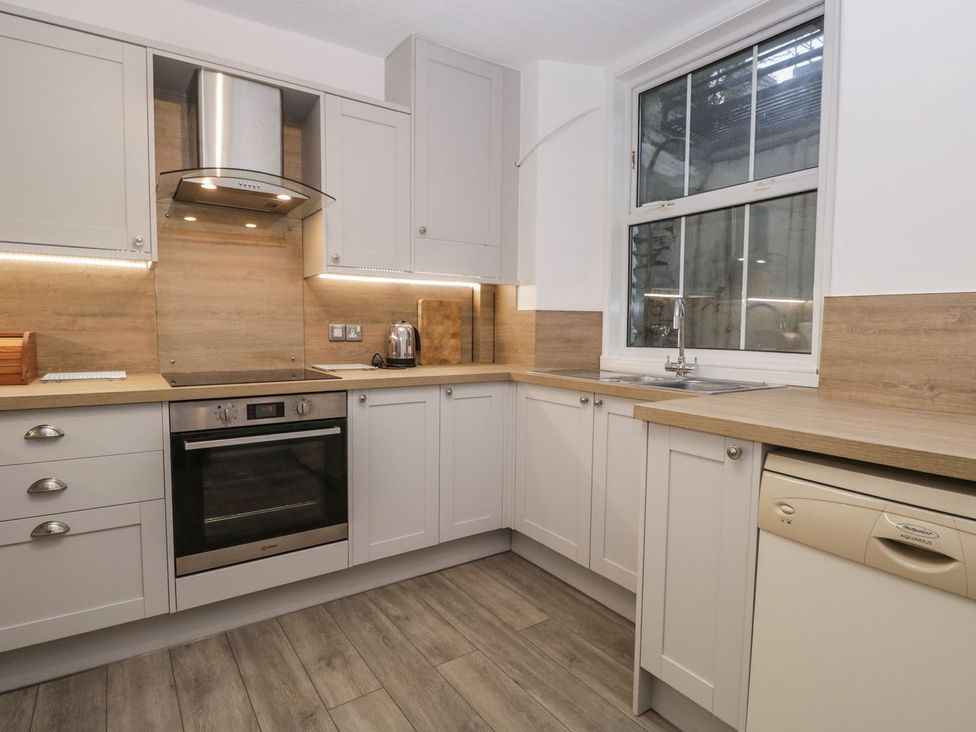 A kitchen with cabinets, stove, sink, and dishwasher at The Burrow in Windermere