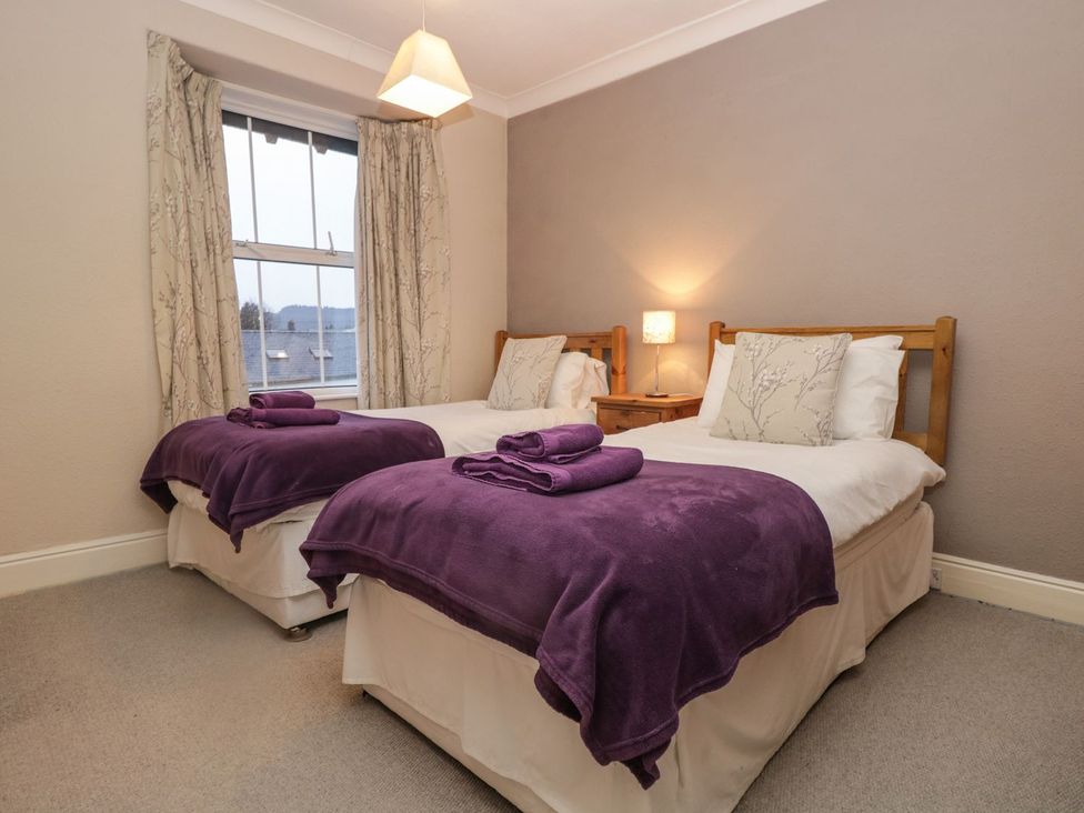 A bedroom with two beds and a bedside table at The Burrow in Windermere