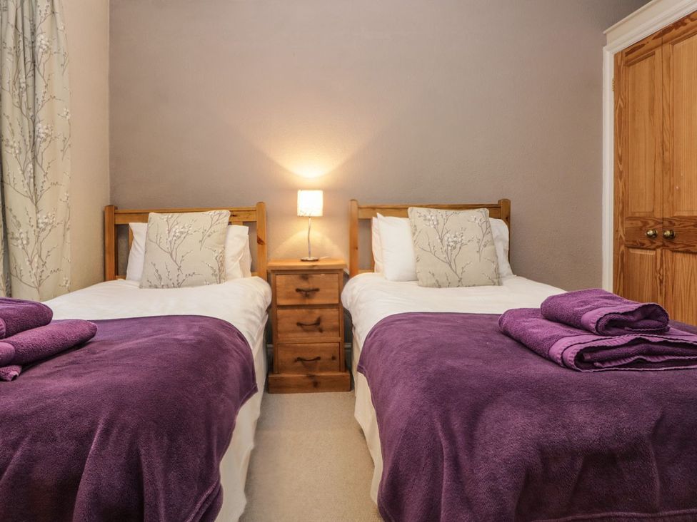 A bedroom with two beds and a bedside table at The Burrow in Windermere