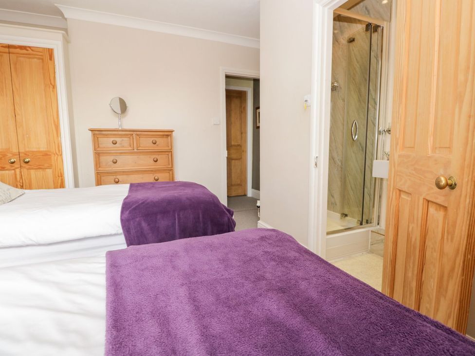 A bedroom with two beds and a shower in the corner at The Burrow in Windermere