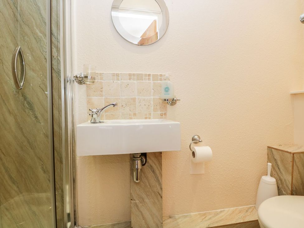 A bathroom with a sink, mirror, and toilet at The Burrow in Windermere