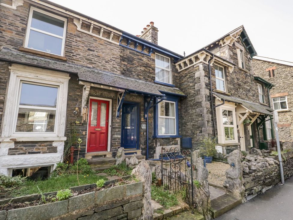 A stone house with red and blue doors and gardens at The Burrow in Windermere
