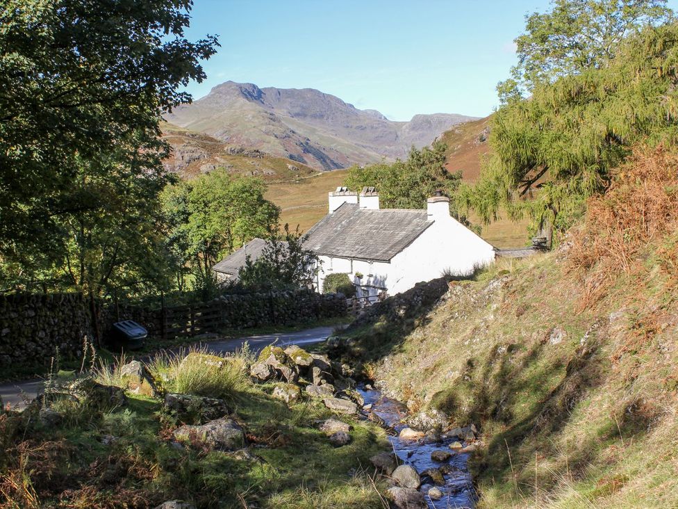 A house near a stream with mountains in the background at The Burrow Windermere