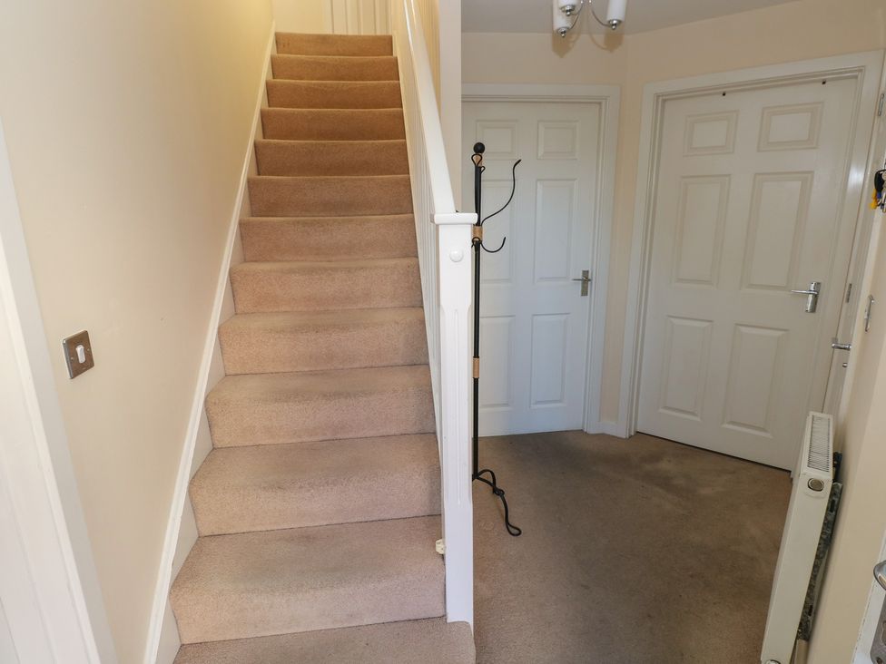 A hallway with a staircase and coat rack at 9 Ffordd Donaldson Swansea