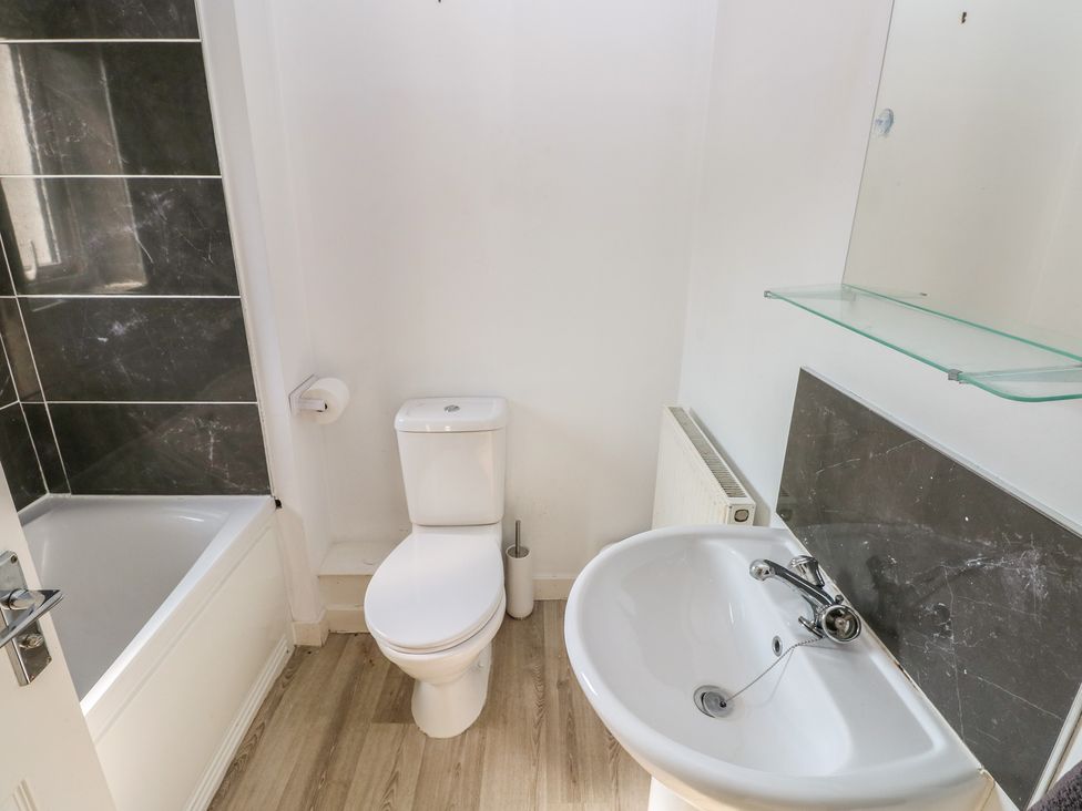 A bathroom with a bathtub, toilet, sink and mirror at Swansea Escape in Swansea