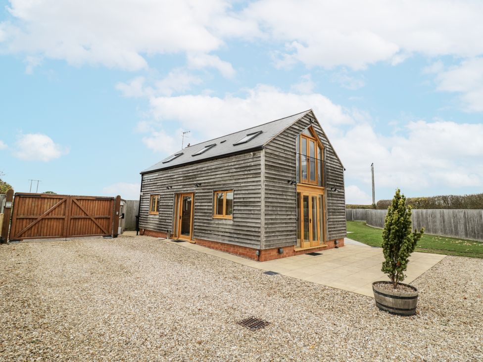 A house with wooden cladding and a gravel driveway at Cedar Barn