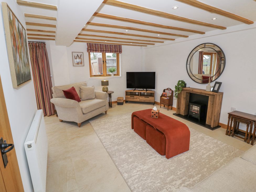 A living room with a sofa, television, and coffee table at Cedar Barn 