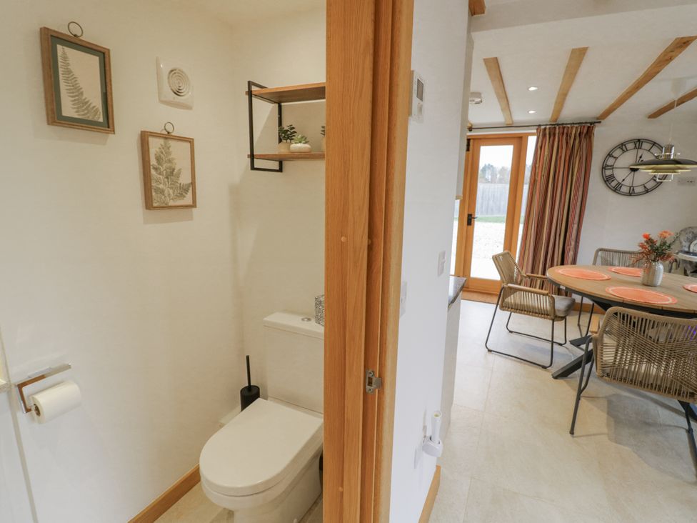 A bathroom with a toilet and wall art at Cedar Barn