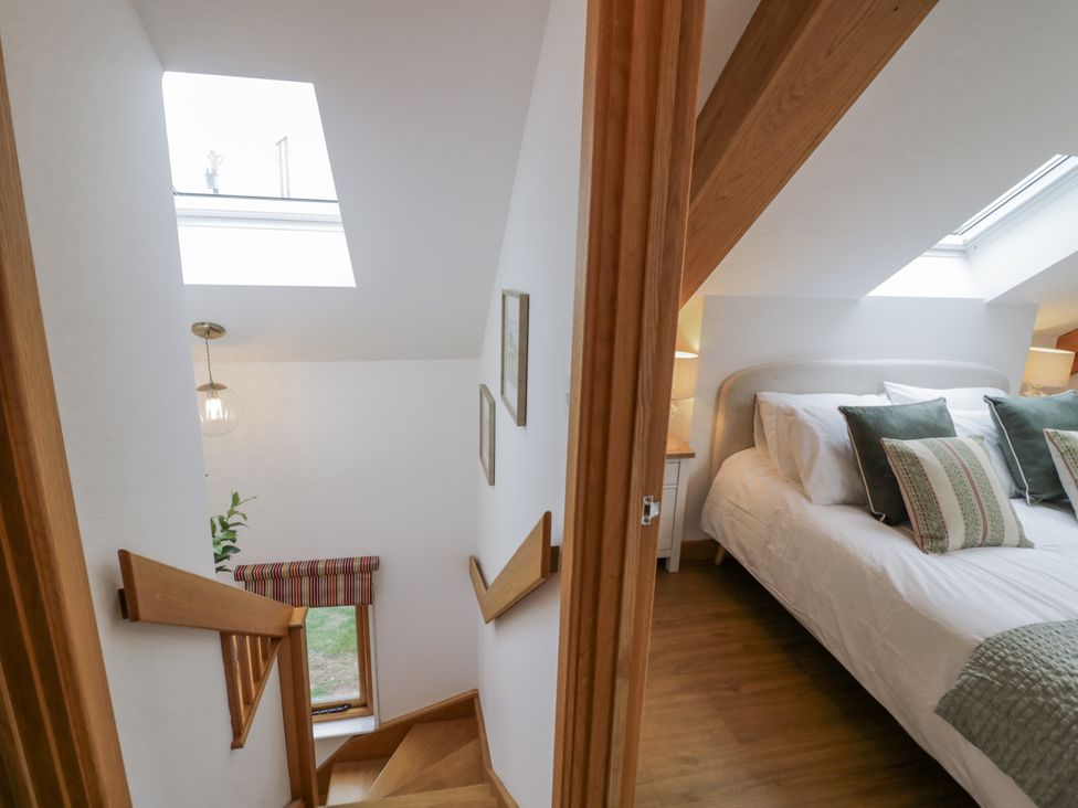 A bedroom with a bed and stairway at Cedar Barn 