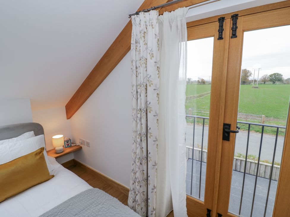A bedroom with a bed and window overlooking a field at Cedar Barn 