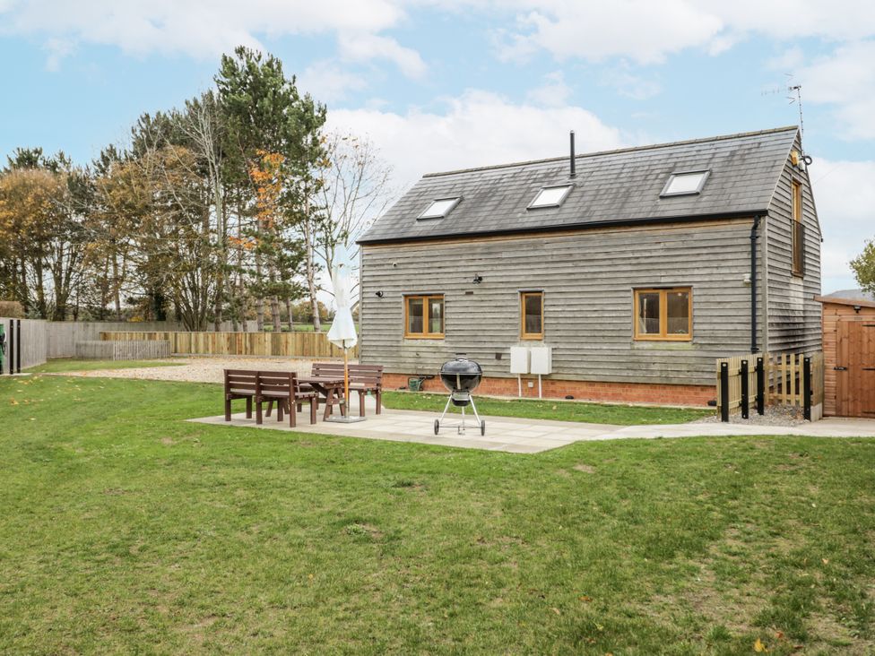 A garden with a wooden house and patio furniture at Cedar Barn