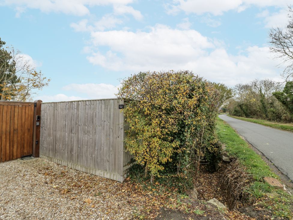An entrance gate with hedge near a road at Cedar Barn 