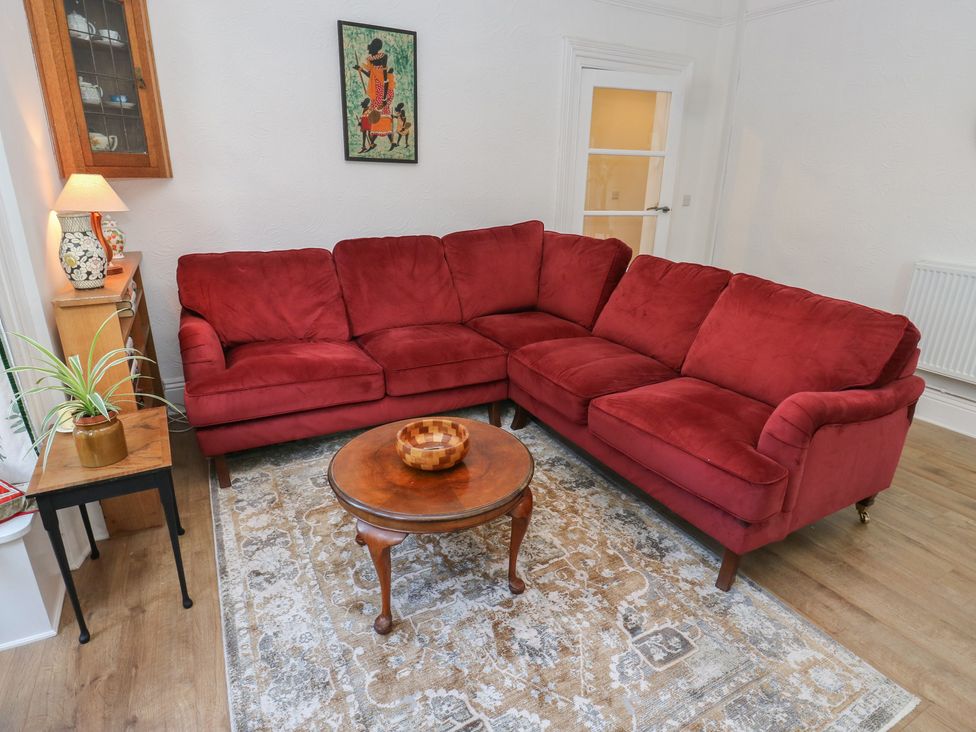 A living room with a red sofa and wooden table at 27 Calton terrace in Skipton
