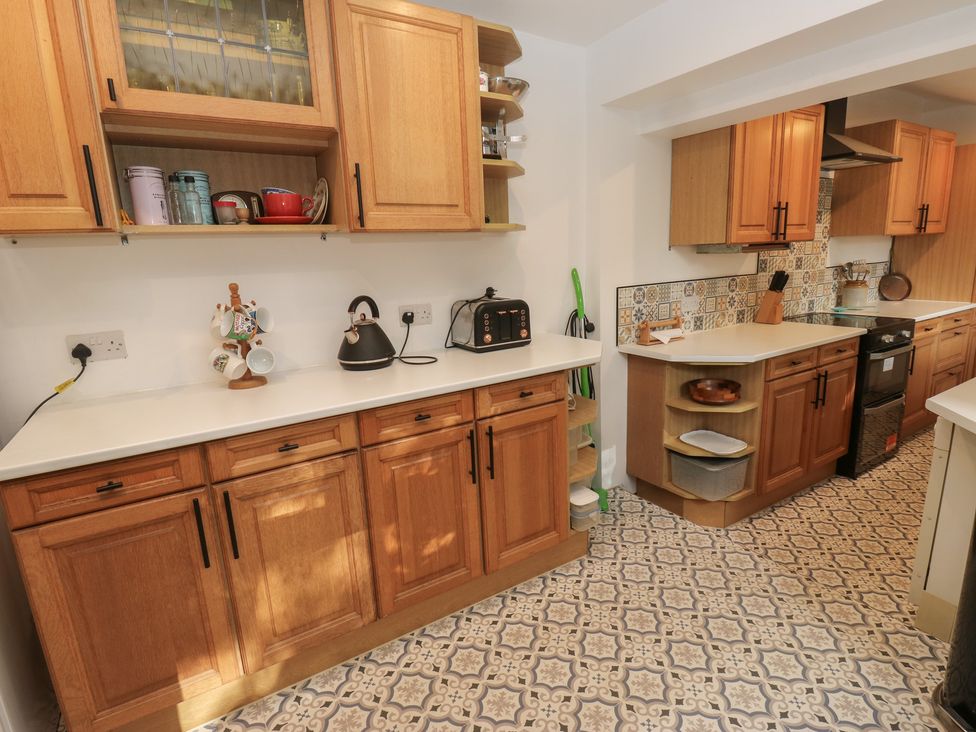 A kitchen with wooden cabinets and various appliances at 27 Calton terrace Skipton