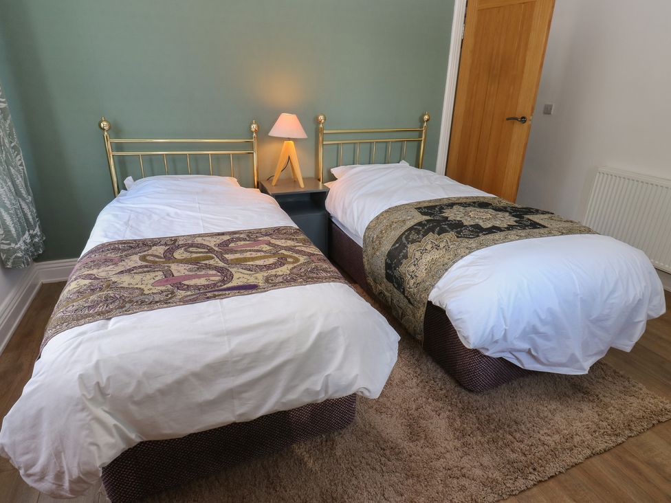 A bedroom with two single beds and a bedside lamp at 27 Calton terrace in Skipton
