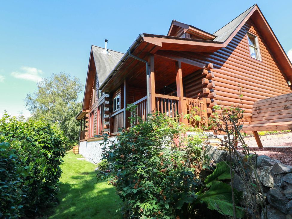 A house with a deck and bench surrounded by grass at Deer’s Leap