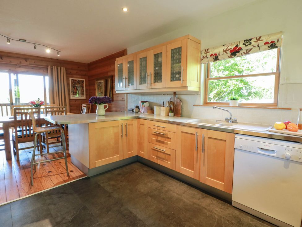 A kitchen with wooden cabinets and a dining area at Deer’s Leap