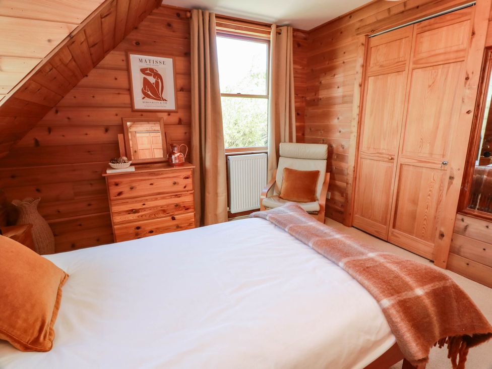 A bedroom with wooden walls and a window at Deer’s Leap