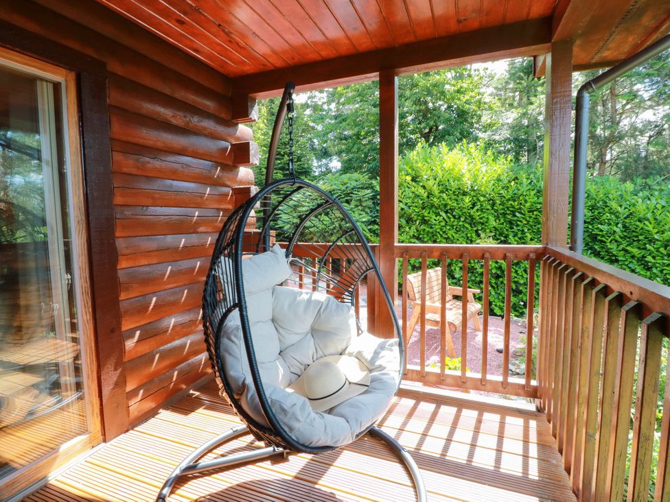 A hanging chair on a balcony with wooden railings at Deer’s Leap