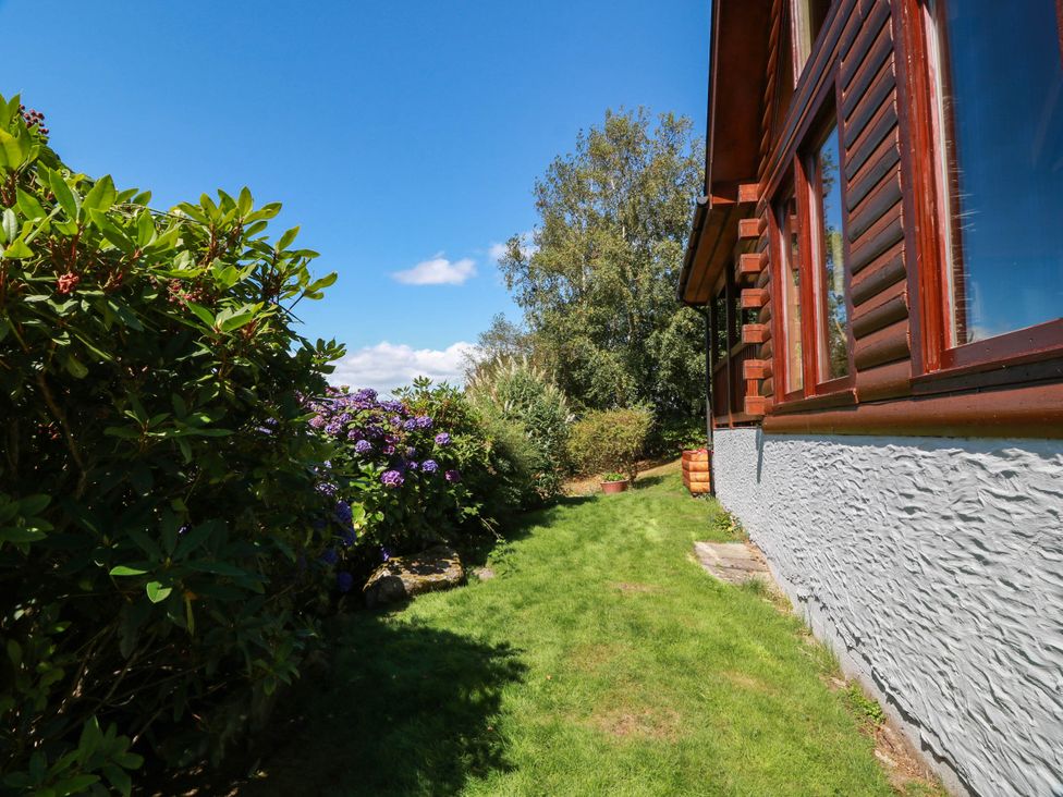 A garden with flowers and grass next to a house at Deer’s Leap