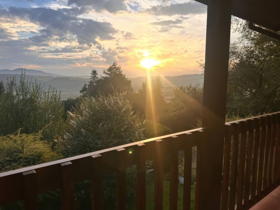 A sunset view with trees and a railing at Deer’s Leap Kippford