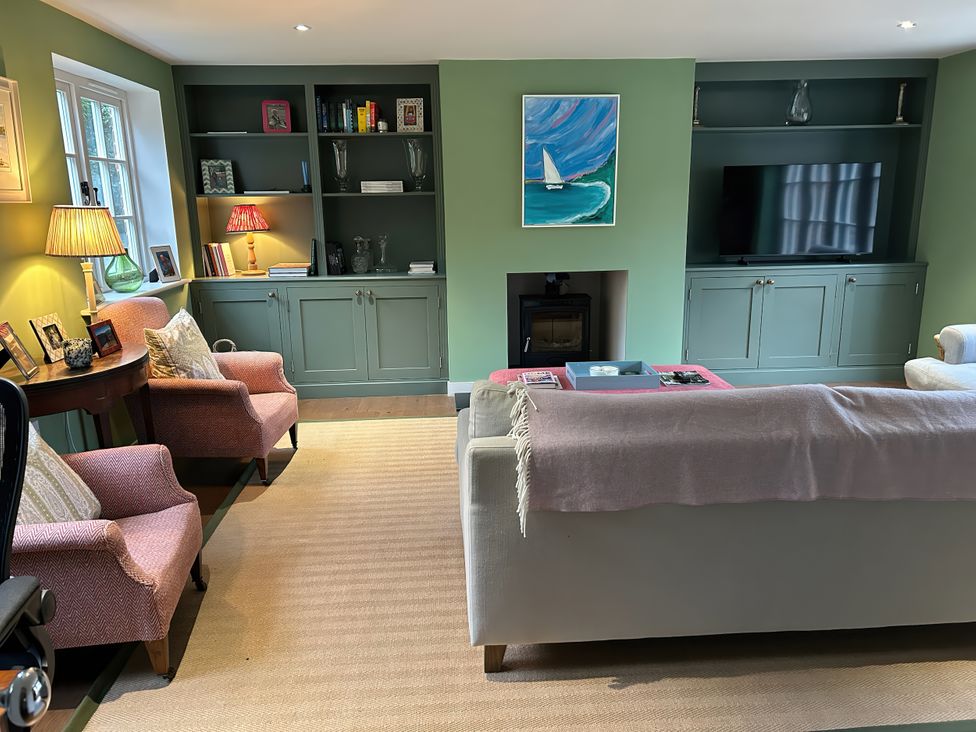 A living room with a sofa, armchairs, a coffee table, and a television at Riverside Cottage