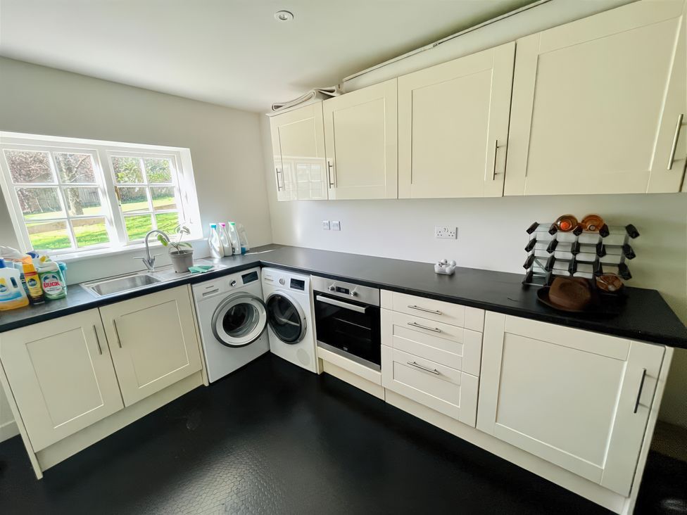 A kitchen with a sink, washing machine, and oven at Riverside Cottage