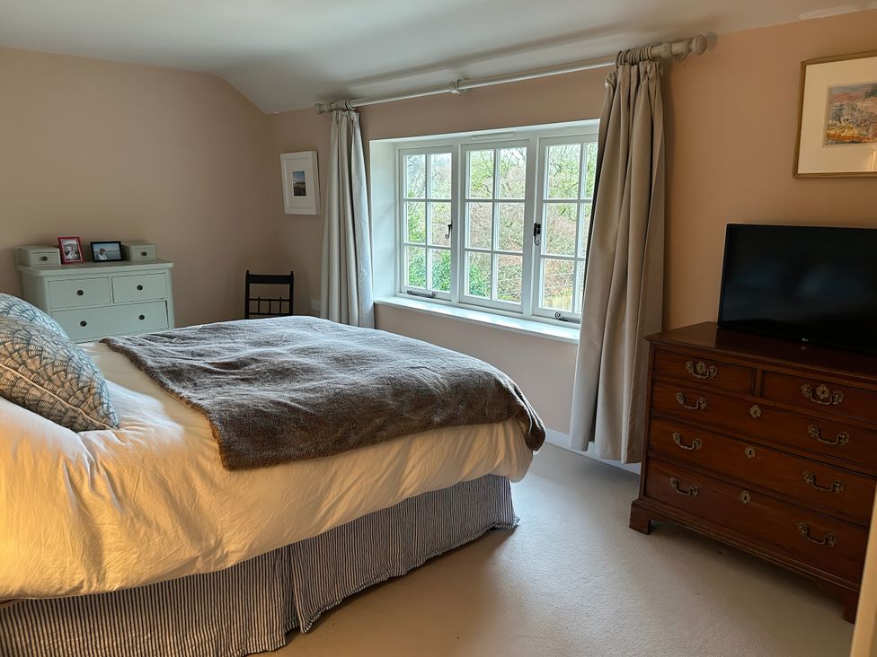A bedroom with a bed and dresser at Riverside Cottage