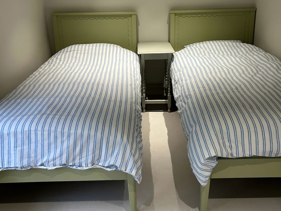 A bedroom with twin beds and a bedside table at Riverside Cottage 