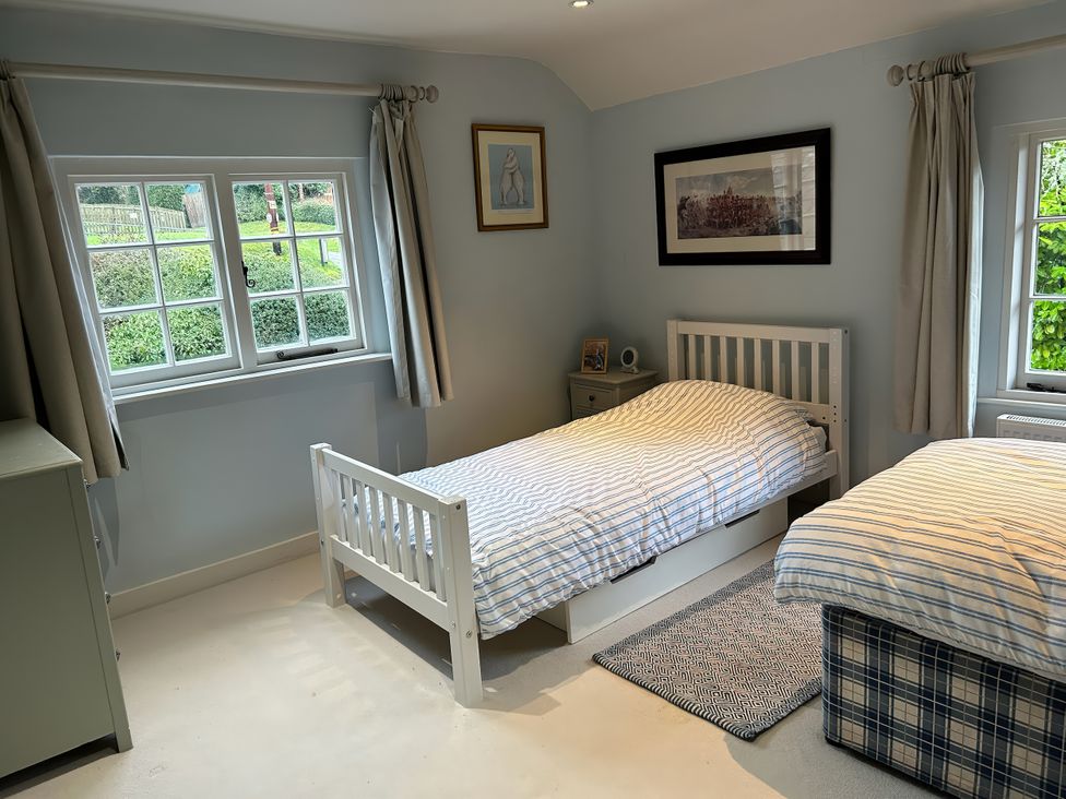 A bedroom with two beds and windows at Riverside Cottage