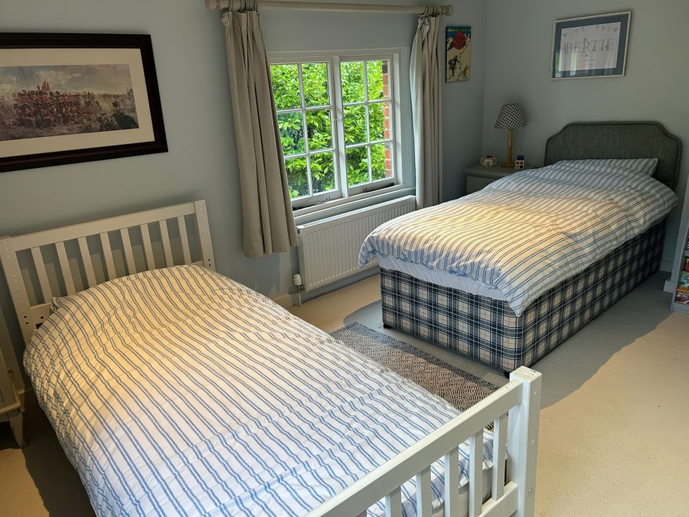 A bedroom with two beds and a window at Riverside Cottage