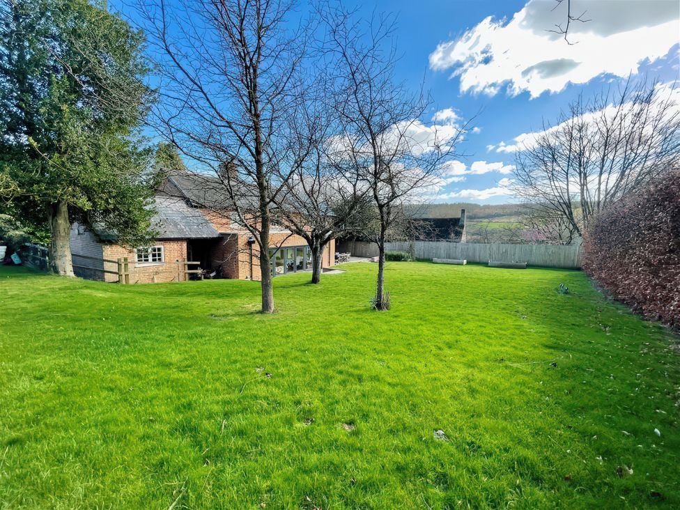 A garden view with trees and a house at Riverside Cottage