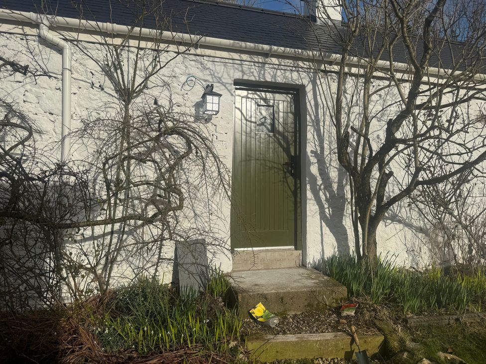 A green door with steps and plants at the Auld Cider Makers Cottage in Portstewart, County Londonderry