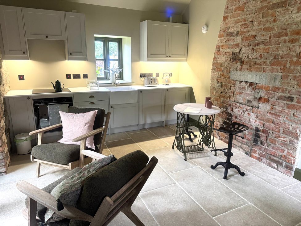 A kitchen with cabinets, a sink, oven, refrigerator, table and chairs at Auld Cider Makers Cottage, Portstewart, County Londonderry