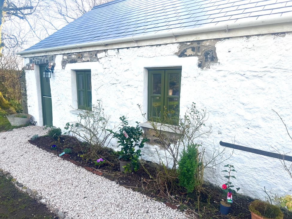 An outdoor view of a white house with green windows and a pathway at Auld Cider Makers Cottage, Portstewart, County Londonderry