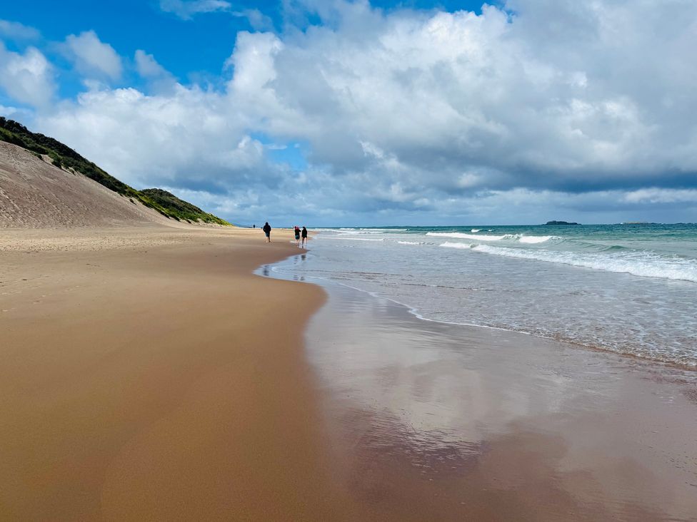 A beach with people walking along the shoreline at Auld Cider Makers Cottage in Portstewart, County Londonderry