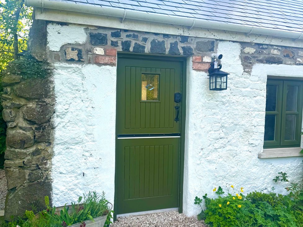 A green door with a window and a stone wall at Auld Cider Makers Cottage, Portstewart, County Londonderry