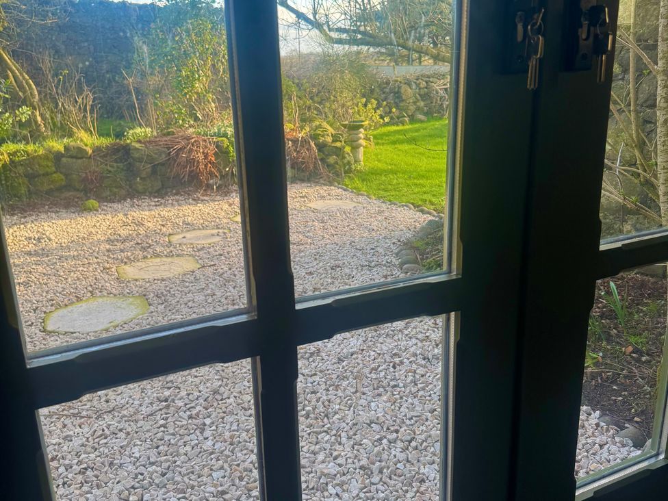 A view of a garden with gravel and stones from a window at Auld Cider Makers Cottage Portstewart, County Londonderry
