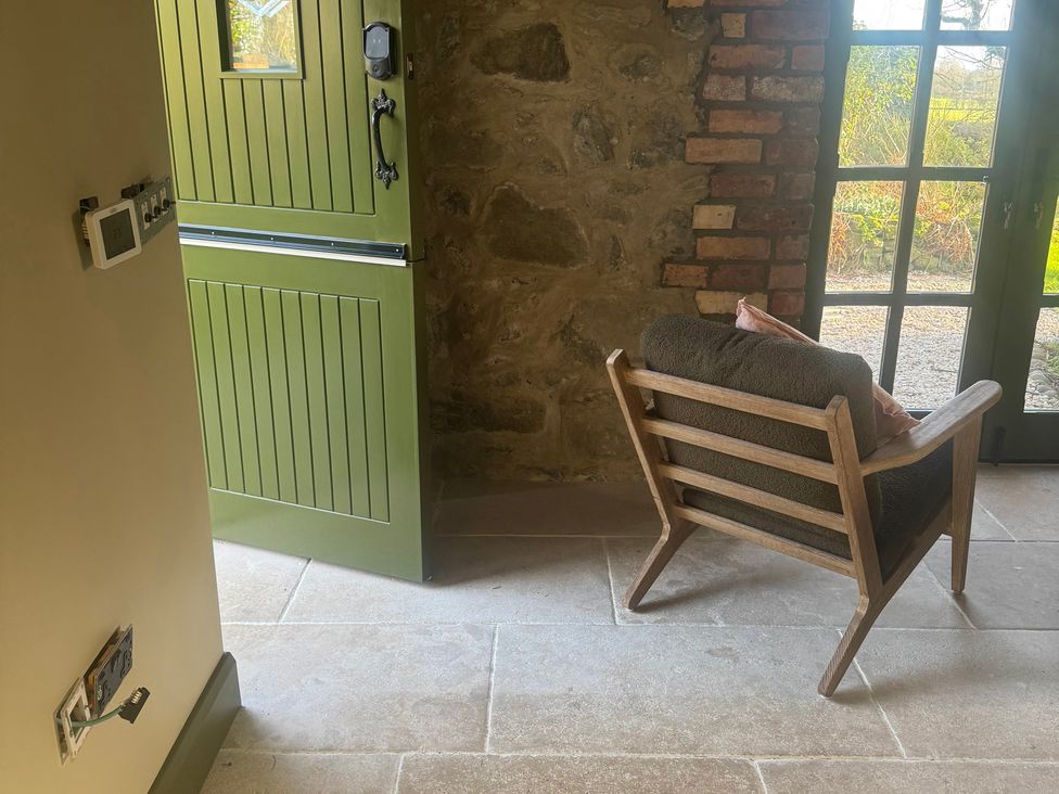 An entrance with a green door and an armchair at Auld Cider Makers Cottage, Portstewart, County Londonderry