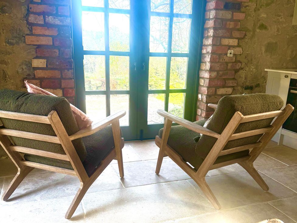 Two chairs facing a door with a view at Auld Cider Makers Cottage in Portstewart, County Londonderry