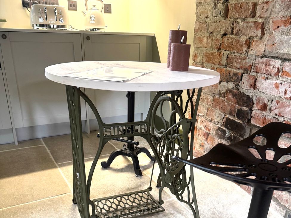A kitchen with a table and stools at Auld Cider Makers Cottage in Portstewart, County Londonderry