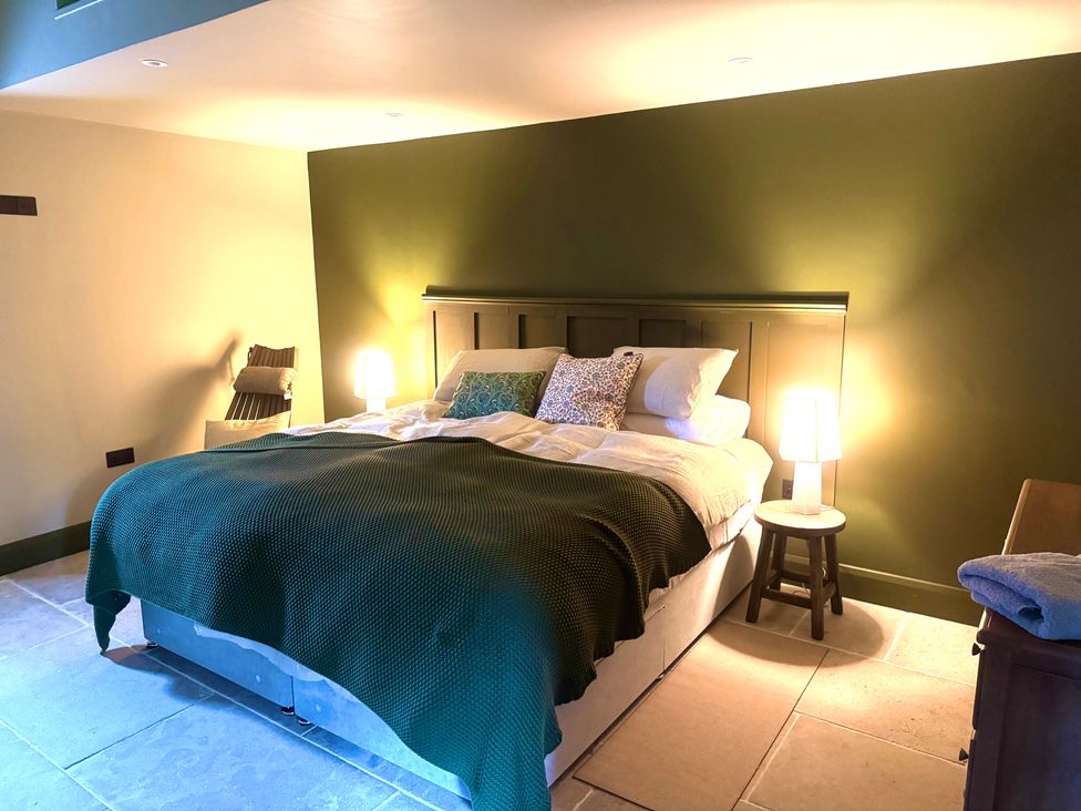 A bedroom with a bed, bedside table, and lamps at Auld Cider Makers Cottage in Portstewart, County Londonderry