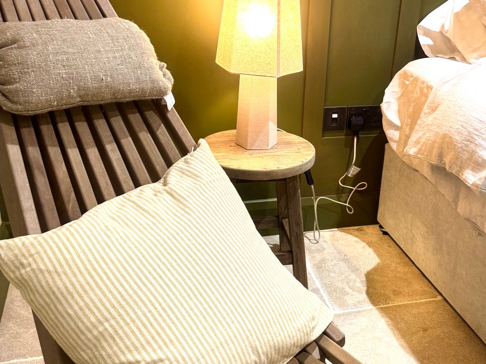 A chair with pillows and lamp beside a bed at Auld Cider Makers Cottage in Portstewart, County Londonderry