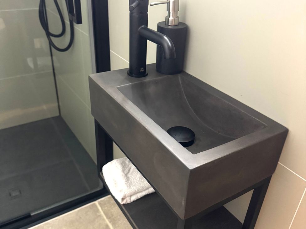 A sink with a black faucet and soap dispenser in a bathroom at Auld Cider Makers Cottage in Portstewart, County Londonderry