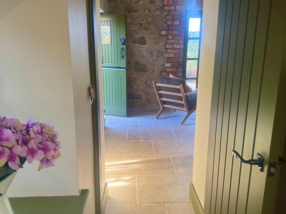 A hallway with a door and an armchair at Auld Cider Makers Cottage, Portstewart, County Londonderry