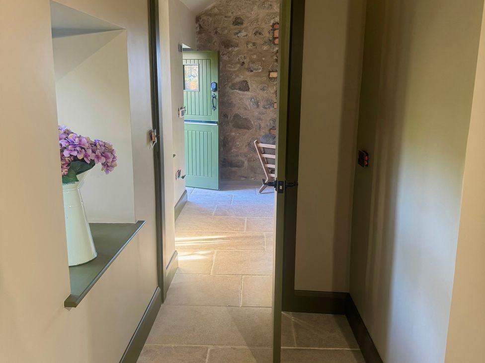 A hallway with a door and flower vase at Auld Cider Makers Cottage in Portstewart, County Londonderry